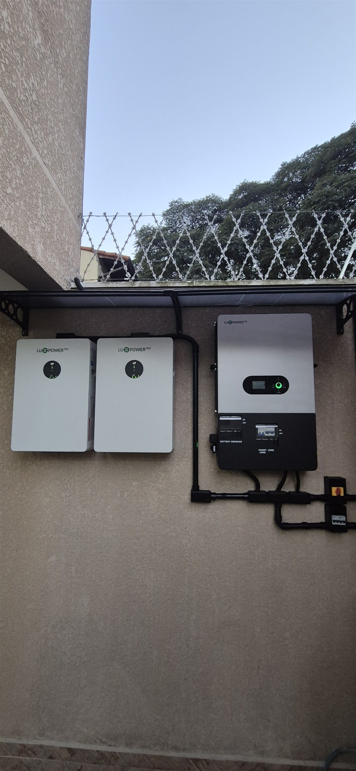 Duas baterias e inversor híbrido instalados pela Renovatech com infraestrutura elétrica aparente organizada